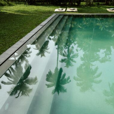 Discover a serene tropical pool surrounded by lush greenery and palm trees, perfect for relaxation.