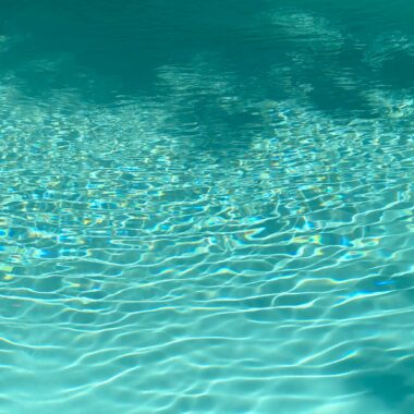 From above of clear blue water of rippling pool on sunny day as abstract background