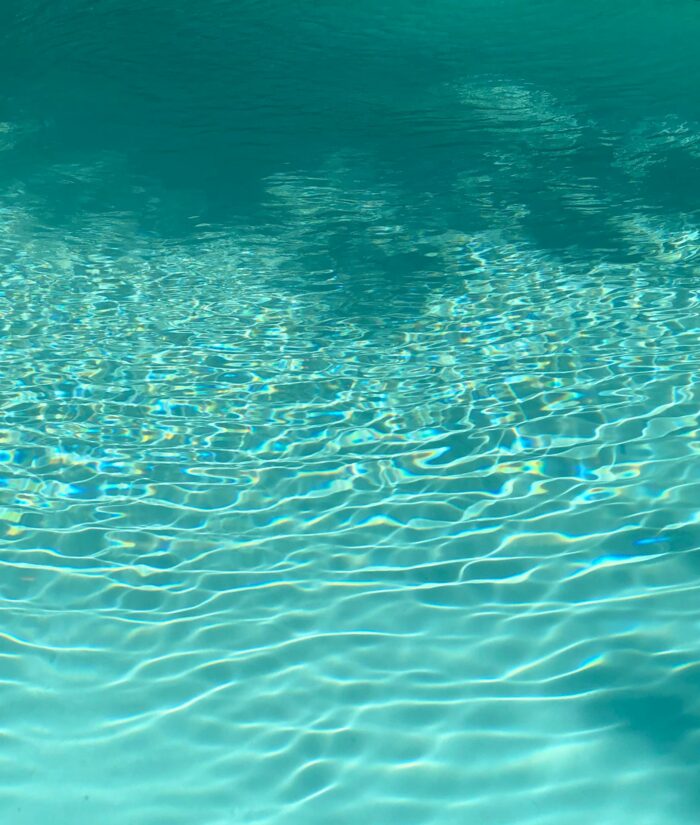 From above of clear blue water of rippling pool on sunny day as abstract background